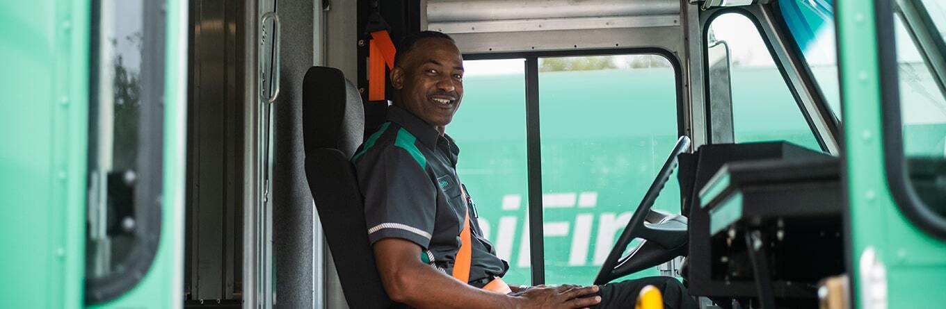 A UniFirst route service representative sits behind the wheel of his UniFirst route truck and gets ready to deliver hygienically cleaned uniforms and facility service products to his customers.