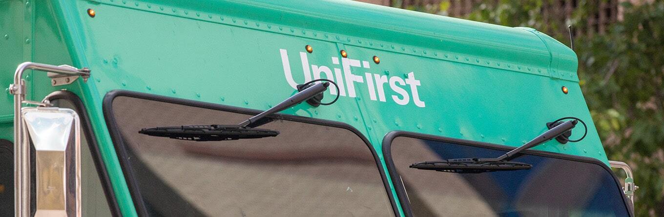 A close up image of the front end of a UniFirst route truck and the UniFirst logo.
