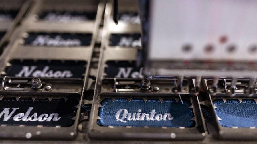 Name plackets being customized in a UniFirst ISO-9001 facility as part of a UniFirst managed uniform rental program.