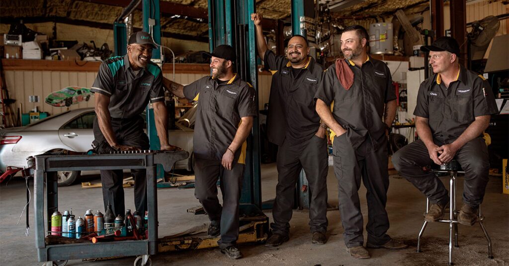 UniFirst RSR standing and laughing with uniformed automotive workers.