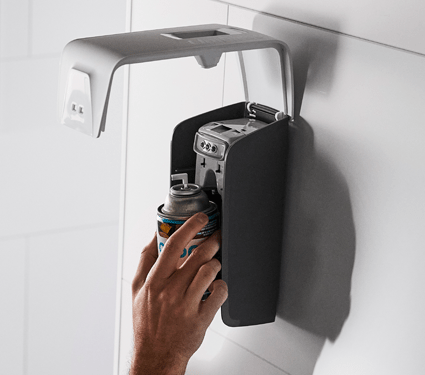 A white Essential Series air freshener dispenser by UniFirst being refilled