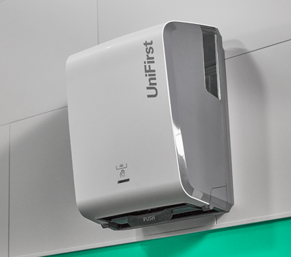 A white Essential Series paper towel dispenser by UniFirst in a commercial restroom