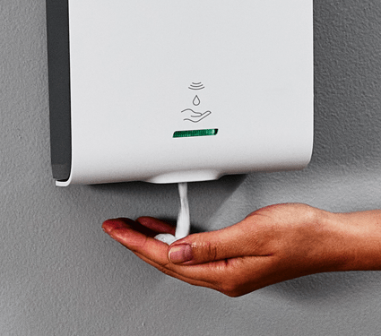 A white Essential Series soap dispenser by UniFirst in a commercial restroom