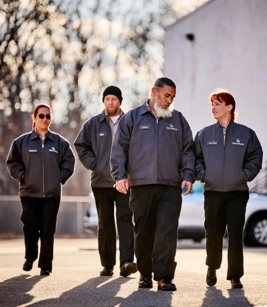 A group of manufacturing workers walk together wearing UniFirst work shirts, work pants, and outerwear