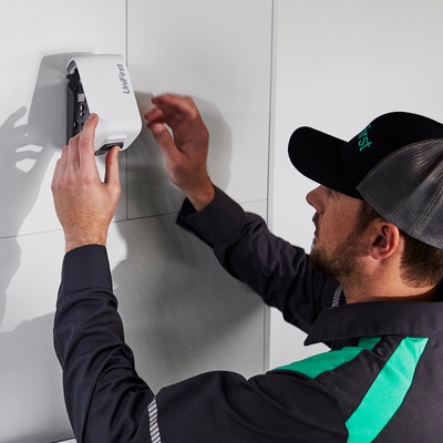 A UniFirst RSR replacing an empty automatic air freshener dispenser with a new refill