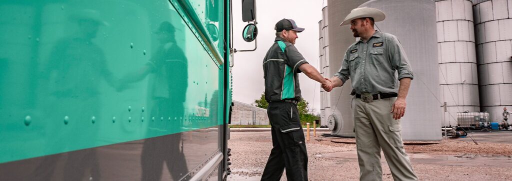 A UniFirst representative shaking hands with a customer discussing uniform rental cost