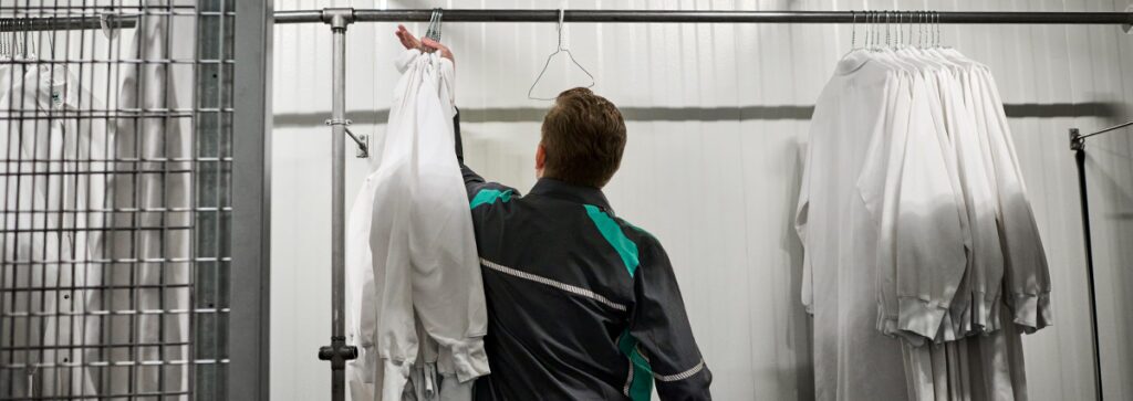 A UniFirst RSR hanging up work shirts at a customer location